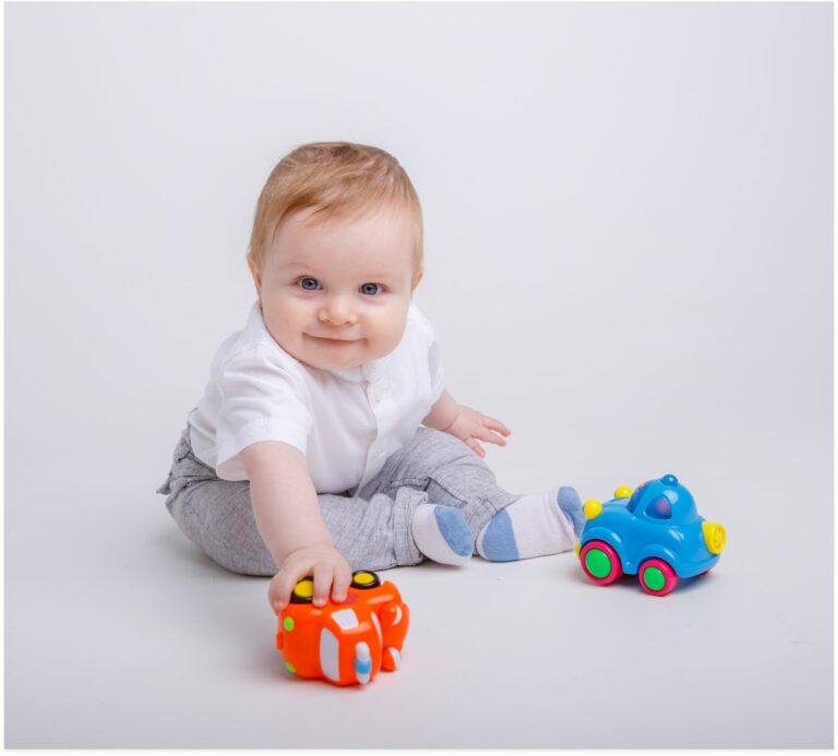 baby-boy-playing-with-toy-cars-on-white-background