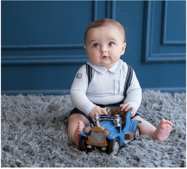 blonde-toddler-sitting-on-carpet-and-playing-with-blue-car